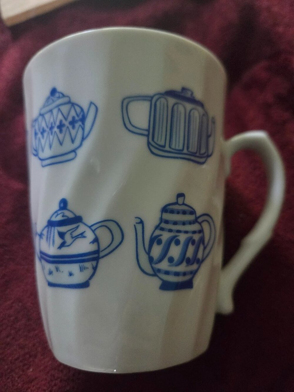 white ceramic mug with blue illustrations of various teapots